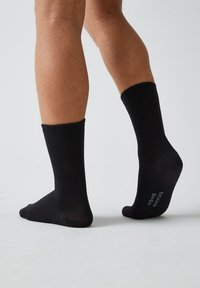 Calze di cotone nere con texture a costine, lunghezza fino al polpaccio e finitura liscia; presenta la taglia e il logo del marchio stampati sulla suola.