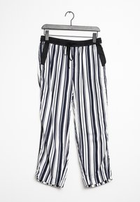 Svarta och vita vertikala randiga byxor med svart elastisk midjeband och dragsko, hängande på en svart metallklädhängare mot vit bakgrund.