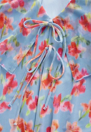 Blumenbluse aus leicht blauer Stoff mit roten und rosa Blumen. Verfügt über einen Kragen und gebundene Details mit bunten Kordeln.