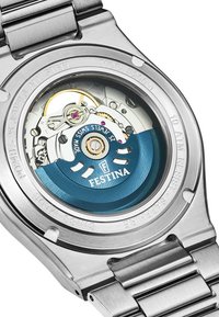 Nerūsējošā tērauda pulkstenis ar caurspīdīgu aizmuguri, kas izceļ zilu un sudraba automātisko mehānismu ar redzamām zobratiem un akcentiem.