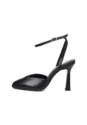 Zwarte leren hoge hak met puntige neus en een dunne enkelband die vastzit met een kleine gouden gesp.