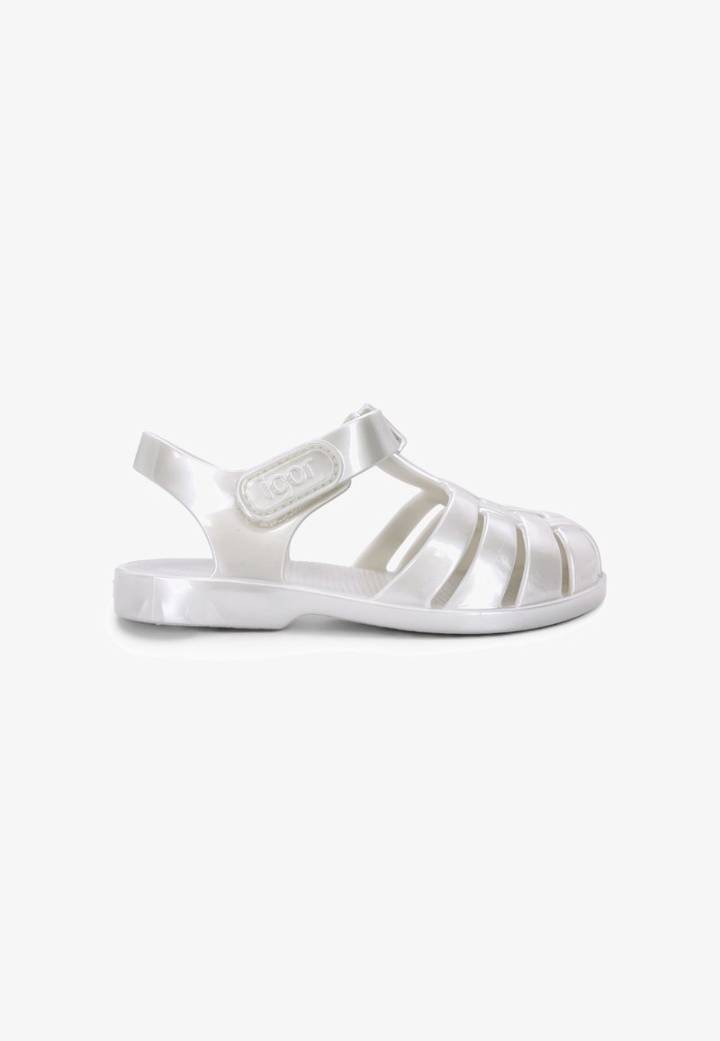 Sandale blanche en plastique type jelly avec bout fermé, côtés ouverts et bride de cheville à fermeture Velcro.