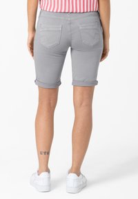 Gray denim bermuda shorts with rolled cuffs, featuring two back pockets. Worn with white sneakers.