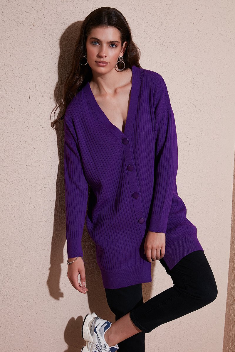 Lila ribbad cardigan med V-hals och fem knappar, tillsammans med svarta byxor. Modellen bär vita och blå sneakers. Texturerat tyg.