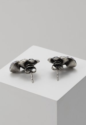 Pair of silver stud earrings with three clear gemstones arranged in a triangular cluster on a white display block.