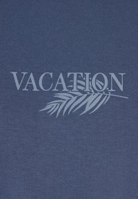 Un tessuto blu presenta la parola "VACANZA" in grigio chiaro, accompagnata da un grafico di foglia di palma. La texture è liscia con un motivo rigato.