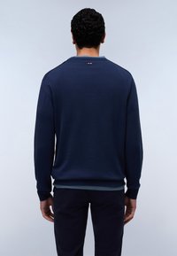 Donkerblauwe trui met lange mouwen, geribbelde manchetten en zoom, minimalistisch ontwerp, met een kleine kleuraccent nabij de halslijn.
