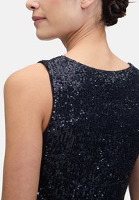 Robe sans manches bleu marine avec une texture en sequins, dotée d'un col rond et d'une coupe ajustée. Éclat subtil des sequins réfléchissants sur toute la surface.
