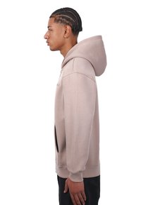 Hoodie beige clair avec une poche kangourou, des poignets côtelés et une capuche avec cordon de serrage. Texture lisse, coupe décontractée, avec un branding minimal.