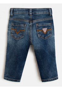 Jeans de bebé de un azul oscuro descolorido con costuras naranjas y dos bolsillos traseros, uno de los cuales presenta un pequeño parche triangular blanco con el logo de Guess.