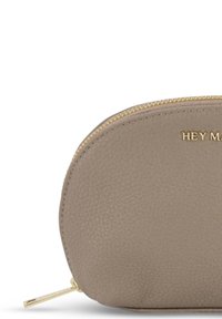 Ronde leren pouch in licht taupe met een gestructureerd oppervlak. Gouden rits en geperst logo "HEY MA" aan de voorkant. Compact ontwerp.