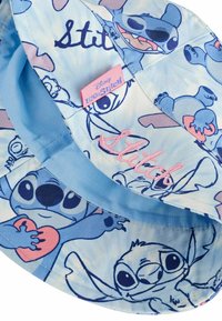 Sininen kangashattu, jossa on Disney'n Lilo & Stitch -elokuvan Stitch. Kuvastuksia eri asennoissa vaaleansinisellä taustalla.