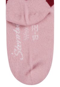 Pink knitted sock with white text and design details on the sole, showing the toe and part of the ankle area.