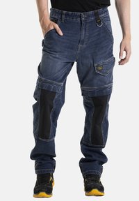 Pantalons cargo en denim avec des panneaux de tissu foncé, plusieurs poches et une coupe décontractée. La taille comprend une boucle et des accents de passant de ceinture.
