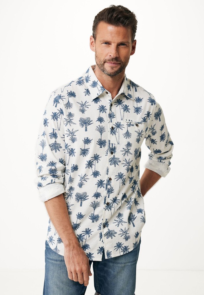 Camicia a maniche corte con bottoni in tessuto leggero, caratterizzata da una base bianca con motivi di palme blu scuro. Colletto classico e maniche arrotolate.