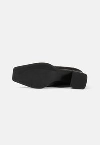 Semelle de chaussure en cuir noir avec une surface lisse, de forme rectangulaire et un léger talon. Caoutchouc texturé pour une bonne adhérence avec un motif de vagues subtil.