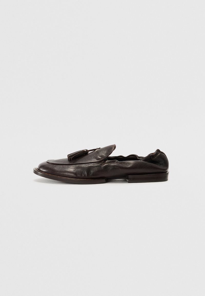 Bruine leren loafer met ronde neus, decoratieve kwastaccent en minimale details. Glad textuur, lage hak en instapontwerp.