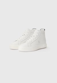 Białe sneakersy typu high-top ze skóry, z białymi sznurówkami, teksturowanymi panelami bocznymi oraz czarnym elementem na pięcie. Posiadają subtelne logo z boku.
