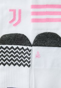 Weiße Socken mit pinken und schwarzen Mustern. Merkmale sind ein Zickzackdesign und drei pinke Streifen. Branding an der Seite in Pink.