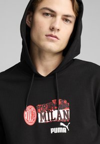 Zwarte hoodie met een grafisch mengsel van de tekst "Forza Milan", rode accenten en logo's van AC Milan en Puma. Zacht materiaal met een standaard pasvorm.
