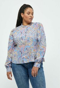 Langærmet bluse i lyseblåt stof med et paisley-mønster i pink, gul og lilla, med rund hals og knapdetaljer.