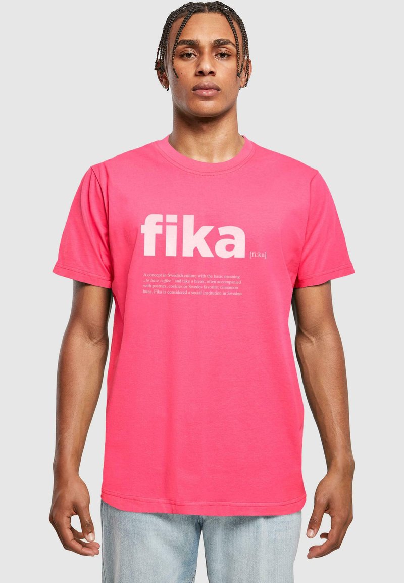 Camiseta de algodón rosa con el gran texto blanco "fika" y una definición debajo. La camiseta tiene mangas cortas y un corte clásico.