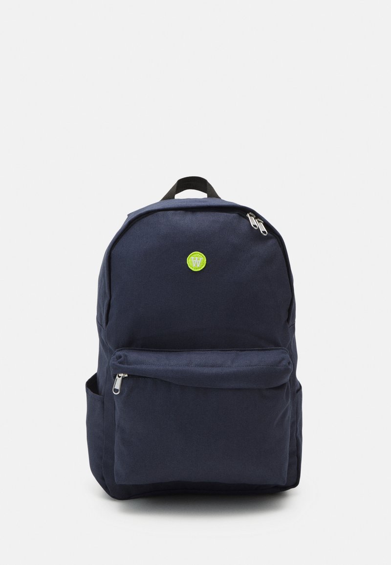 Navy blue backpack made of fabric, featuring a front zipper pocket, logo detail in bright green, and black adjustable shoulder straps.