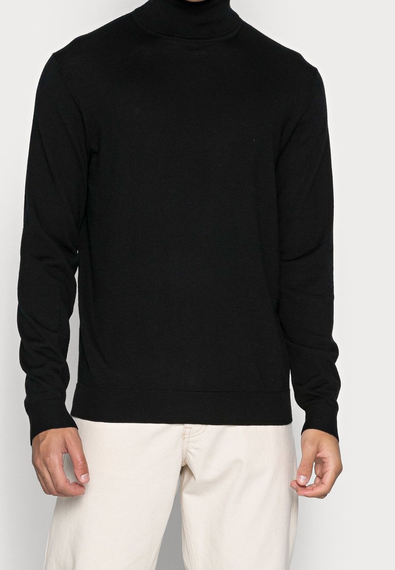 Zwarte coltrui van gebreide stof, met lange mouwen, geribbelde manchetten en een geribbelde onderrand. Gladde textuur en slim fit.