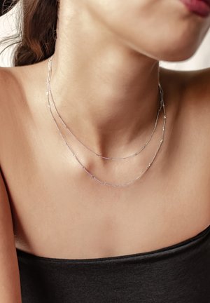 Collana a strati in argento con più catene delicate di lunghezze variabili. La superficie liscia esalta il design elegante.