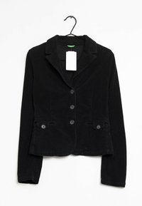 Černý kordový blazer s klopami, dvěma předními kapsami a třemi knoflíky. Visí na černém háčku s bílou cenovkou.