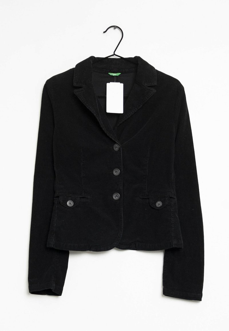 Černý kordový blazer s klopami, dvěma předními kapsami a třemi knoflíky. Visí na černém háčku s bílou cenovkou.