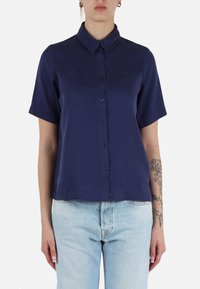 Camicia a maniche corte, con bottoni, di colore blu navy, realizzata in tessuto leggero. Presenta un colletto classico e una cucitura sottile all'orlo.