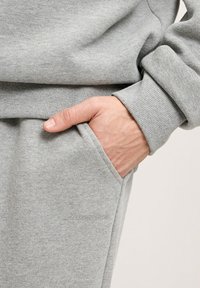 Szara bluza z rękawami w ściągaczu, z boczną kieszenią i dyskretnym logo. Wykonana z miękkiej, teksturowanej tkaniny dla wygody.