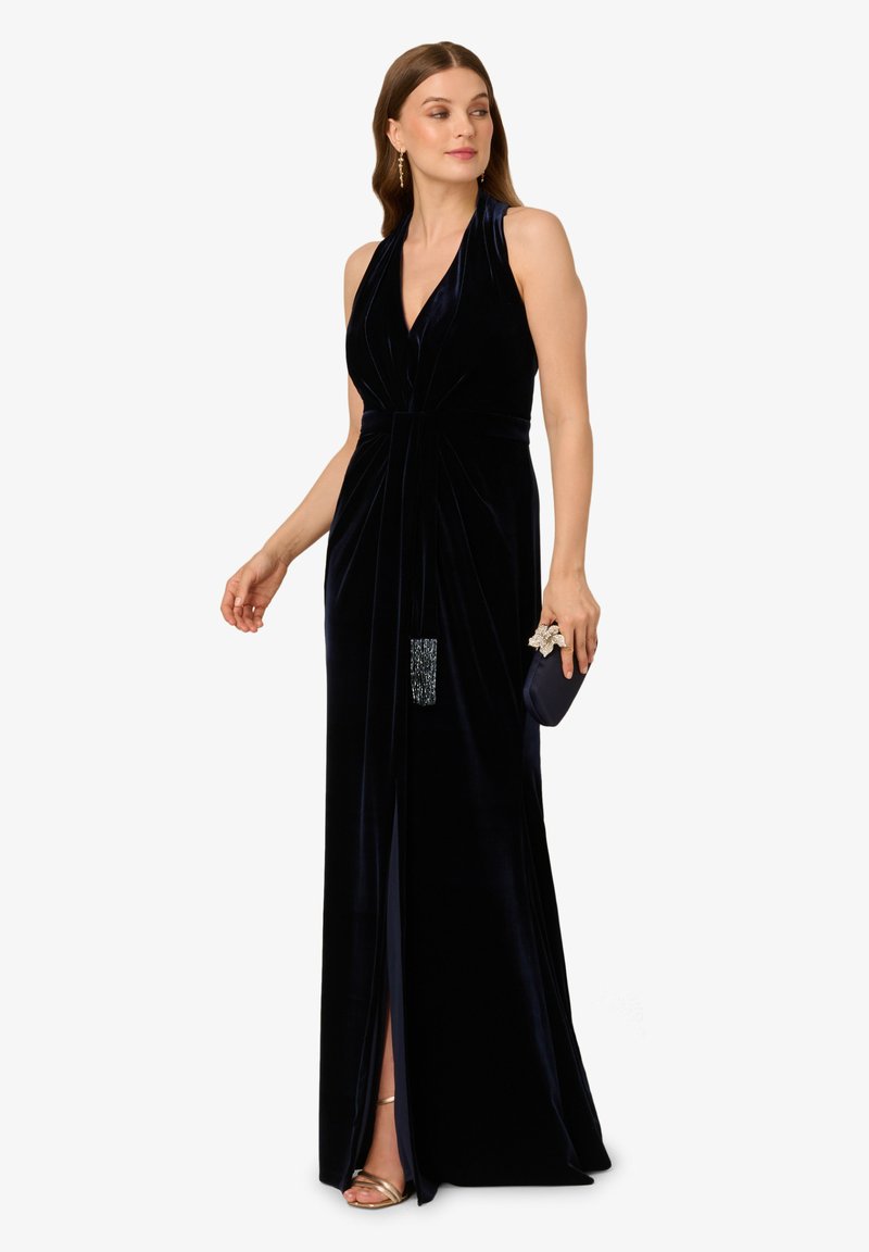 Sukienka z aksamitu w kolorze granatowym, długości do łydki, z halterem, marszczeniami, rozcięciem z przodu oraz koralikowym akcentem w okolicy talii.