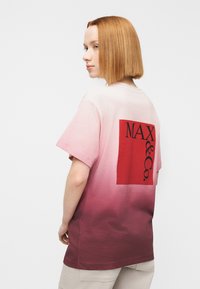 Κοντομάνικο μπλουζάκι με σχέδιο διαβάθμισης από ανοιχτό ροζ σε βαθύ κόκκινο, με ορθογώνιο λογότυπο σε κόκκινο στο πίσω μέρος. Βαμβακερό υλικό, άνετη εφαρμογή.