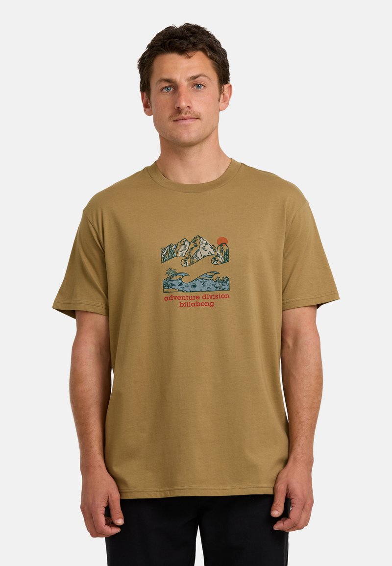 Khaki t-shirt wykonana z bawełny, z niebieską grafiką gór i fal, czerwoną słońcem oraz napisem "adventure division billabong" na środku.