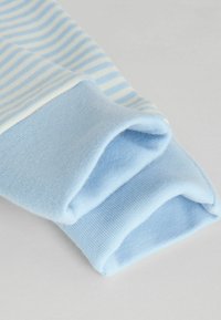 Modrý a biely pruhovaný manžet na dlhý rukáv, s jemnou textúrou a svetlomodrým lemom, zrolovaný s hladkým povrchom.