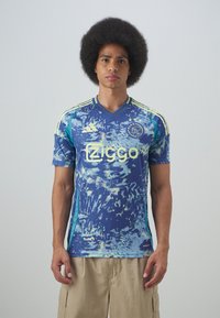 Maglietta da football a maniche corte, con motivo blu e verde acqua, caratterizzata da un collo a V, logo e dettagli gialli sulle spalle e ai lati.