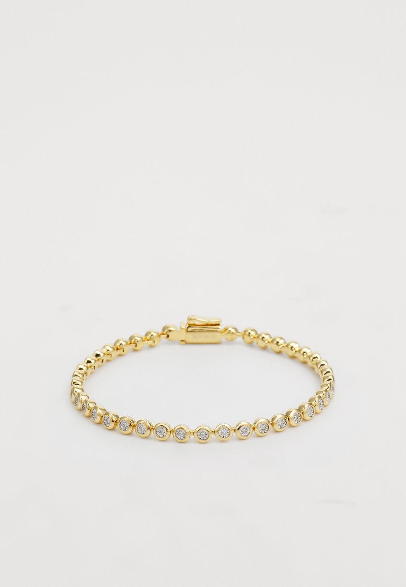 Arany fém karkötő, egyenletes mintázatban elhelyezett kerek, tiszta strasszkövekkel, az egyik oldalon kapcsos záródással. Simább textúra és fényes felület jellemzi.