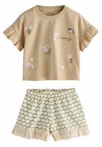 Kortærmet beige top med blomsterbroderi og teksten "happy", parret med grønne shorts med zigzag-mønster og blondekant.