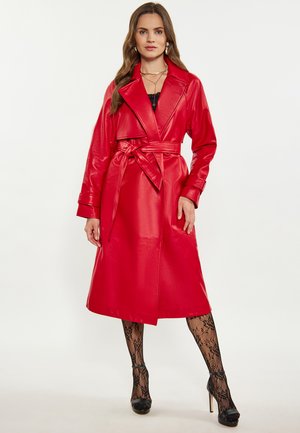 Rode nepleren trenchcoat met een ceintuur in de taille, grote revers en lange mouwen. Getextureerde zwarte kant kousen en hoge hakken maken de look compleet.