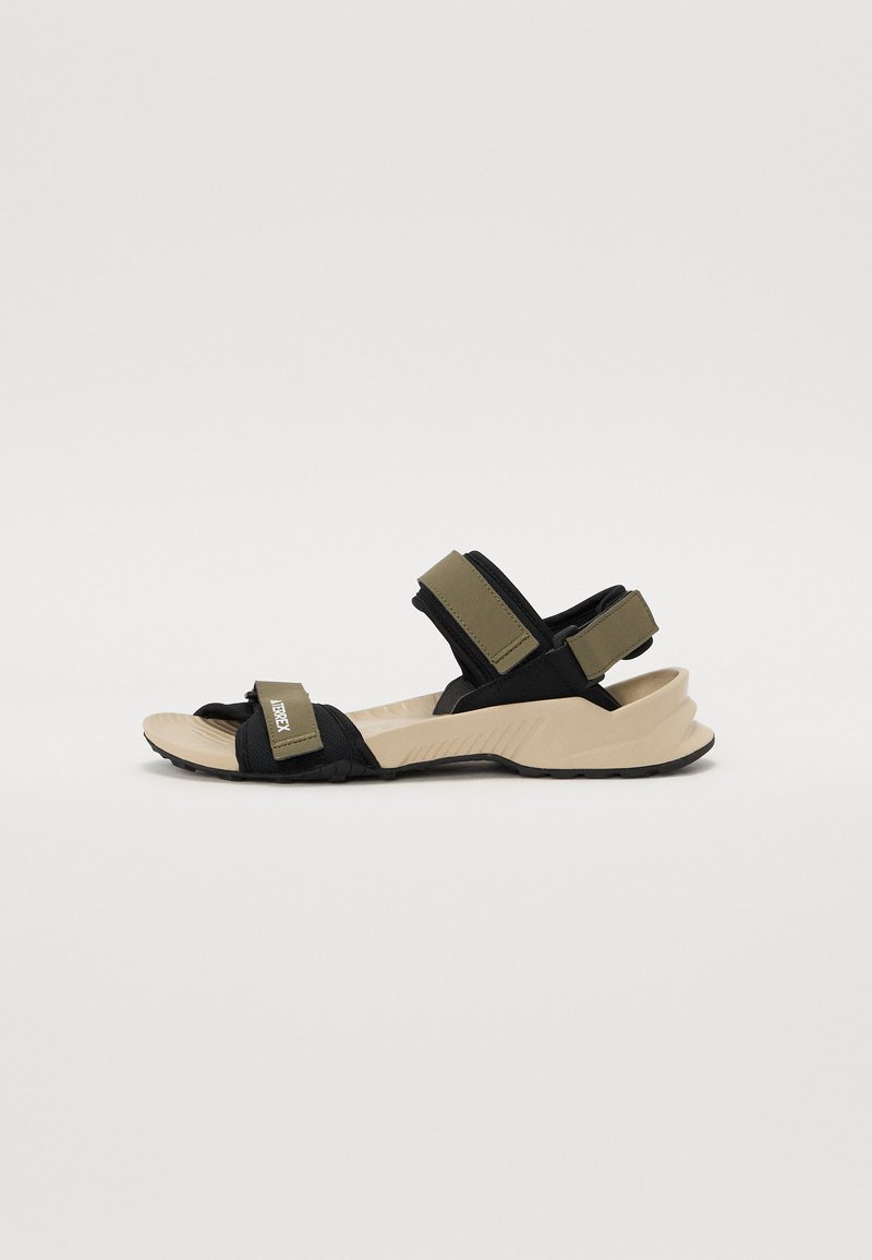 Sandales noires et vert olive avec des sangles réglables, une semelle intérieure beige rembourrée et une semelle en caoutchouc noir texturé. Design léger.