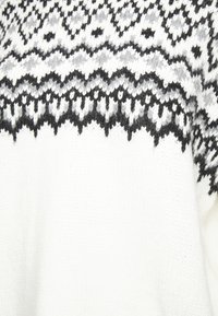 Weißer Strickpullover mit einem schwarz-grauen geometrischen Muster am Ausschnitt. Weicher Stoff mit einem gewellten Saum am unteren Rand.