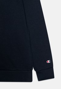 Marinblå sweatshirt med strukturerad tyg, ribbade manschetter och broderad logotyp på vänster ärm. Enkel, avslappnad design.