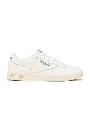 Białe sneakersy Reebok z zielonym logo, niskim fasonem, białymi sznurówkami i beżową gumową podeszwą, przedstawione z profilu na białym tle.