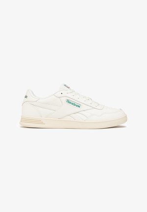 Baskets Reebok blanches avec logo vert, design bas, lacets blancs et semelle en caoutchouc beige, présentées de profil sur fond blanc.