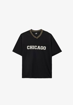 Camiseta negra de manga corta con cuello en V, que presenta "CHICAGO" en letras blancas y doradas en el pecho y costuras de contraste.