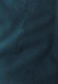 Turkusowy, teksturowany materiał o gładkim wykończeniu; zawiera widoczne detale szwów bez ozdób lub wzorów.