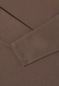 Hnědá košile s dlouhým rukávem a měkkou texturou. Má ploché švy a jednoduchý design, který zdůrazňuje hladký materiál a hlubokou barvu.