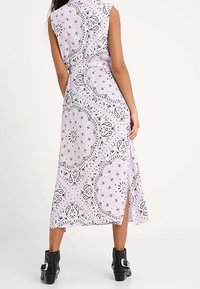 Lila sukienka midi bez rękawów z czarnym wzorem paisley, z bocznym rozcięciem i dopasowanym wcięciem w talii. Stylizowana z masywnymi czarnymi botkami za kostkę.